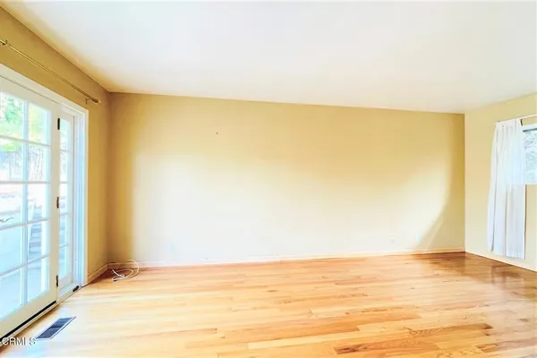a view of an empty room with wooden floor and a window