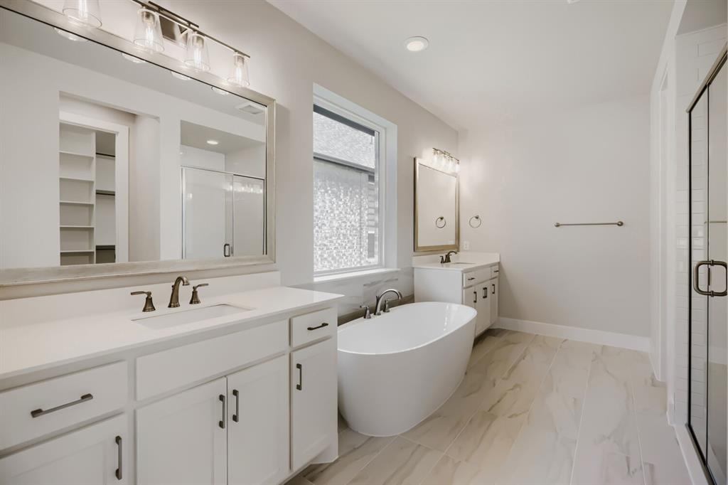 4407 Windy Point Road Oak Point, TX 75068 - Photo 20 of 27 Freestanding soaking tub with a wall-mounted faucet, complemented by dual vanities with white cabinetry and quartz countertops