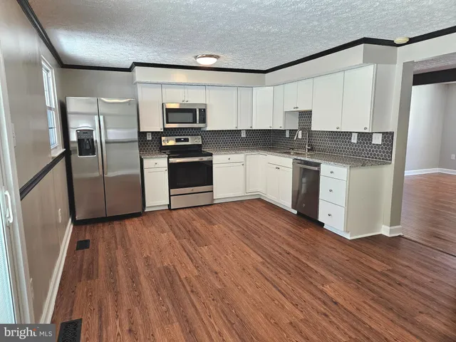 a kitchen with granite countertop a refrigerator and a stove top oven