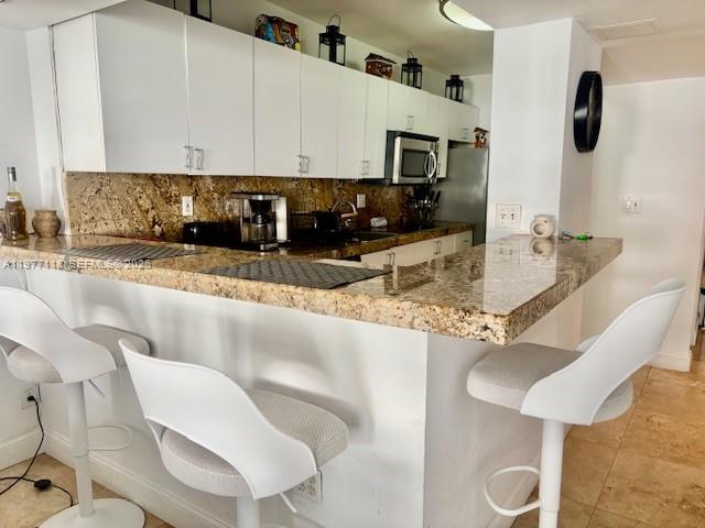 100 Lincoln Road, Unit 531 Miami Beach, FL 33139 - Photo 6 of 31 a kitchen with stainless steel appliances granite countertop a sink a microwave and chairs