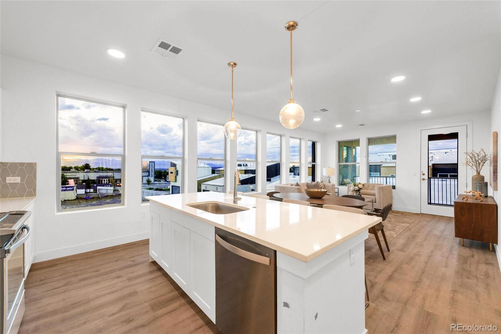 2899 West 52nd Avenue, Unit 301 Denver, CO 80221 - Photo 15 of 16 a view of a kitchen with kitchen island a large counter top space a sink stainless steel appliances and windows