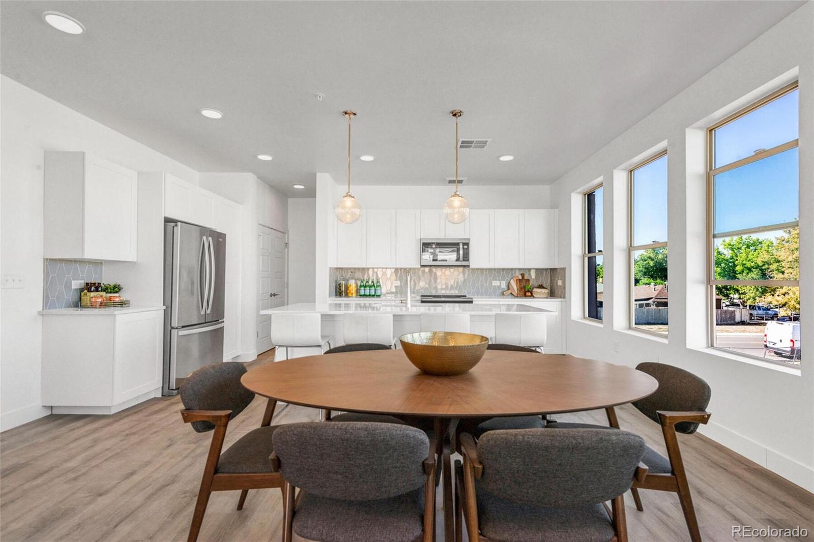 2899 West 52nd Avenue, Unit 301 Denver, CO 80221 - Photo 2 of 16 a kitchen with a dining table chairs and refrigerator