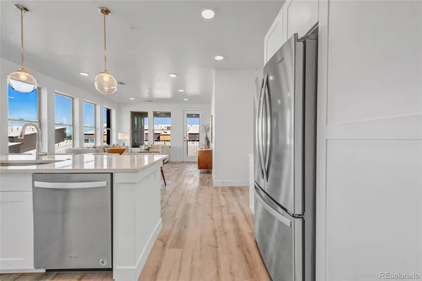 a view of a kitchen with kitchen island wooden floor center island and stainless steel appliances