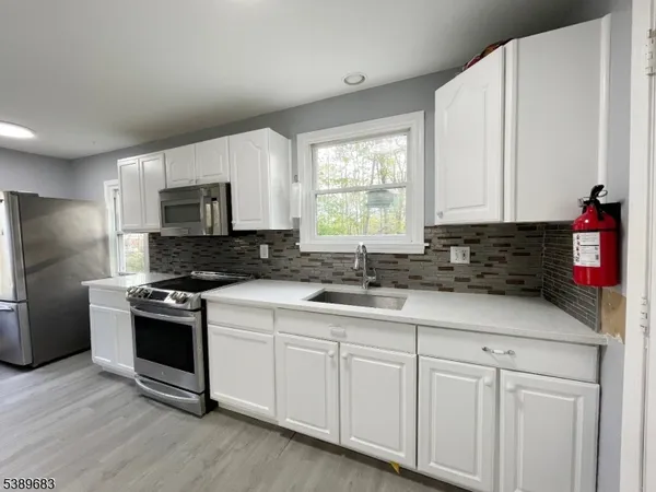a kitchen with granite countertop white cabinets and stainless steel appliances