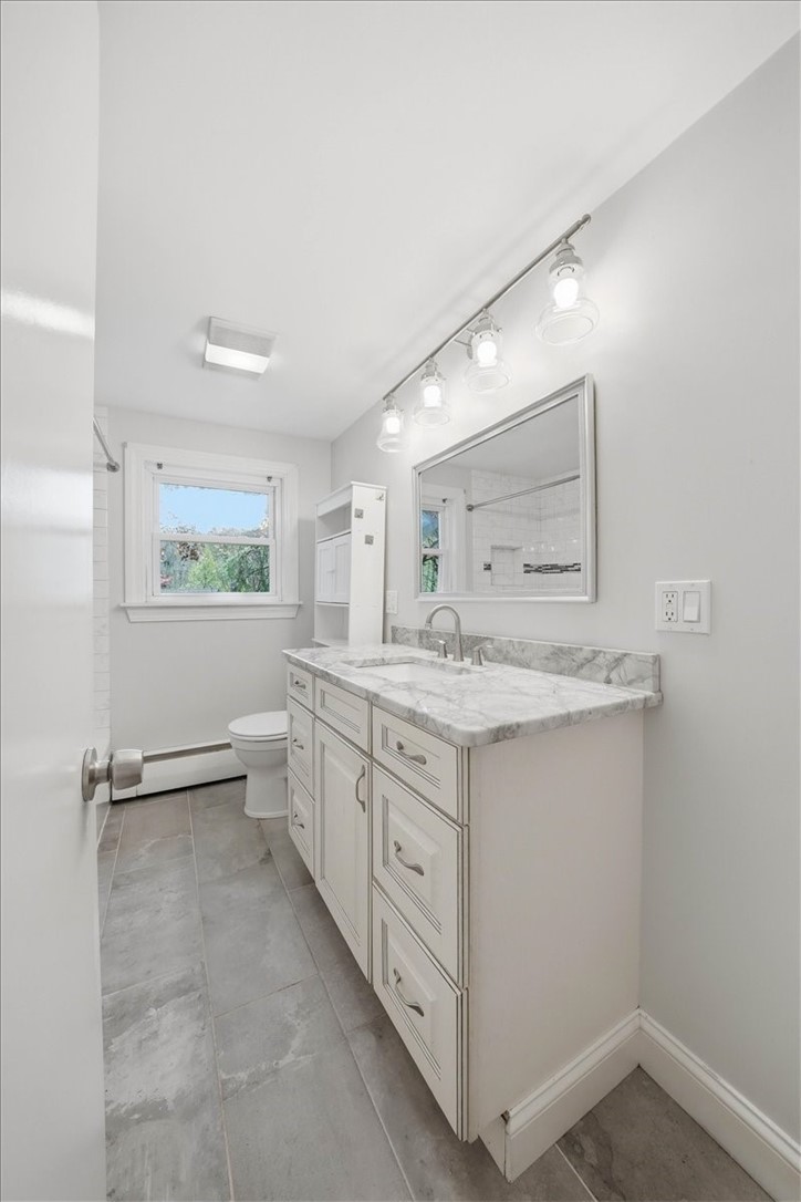 322 Rocky Hill Road Scituate, RI 02857 - Photo 35 of 50 Beautifully renovated full bath showcasing a clean, modern design with timeless finishes. Features include a marble-top vanity with soft-close cabinetry, brushed nickel fixtures, and a sleek framed mirror with updated lighting.