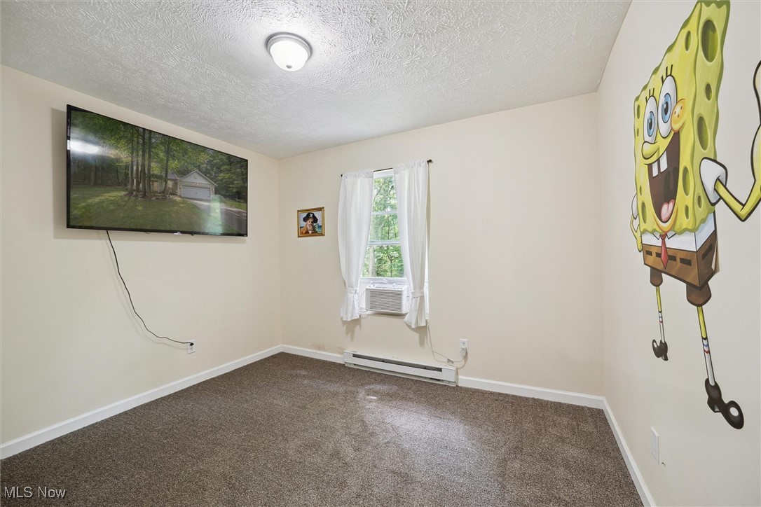 938 Long Shadow Lane Rome, OH 44085 - Photo 27 of 48 Carpeted empty room featuring a textured ceiling, a baseboard radiator, and cooling unit