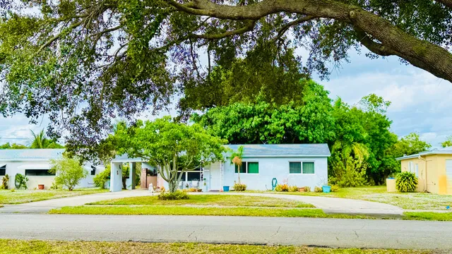 a front view of a house with a garden and trees