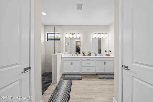 a bathroom with a double vanity sink mirror and shower