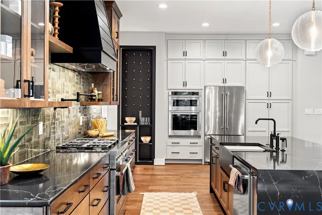 a kitchen with stainless steel appliances granite countertop a stove top oven a sink a refrigerator and white cabinets