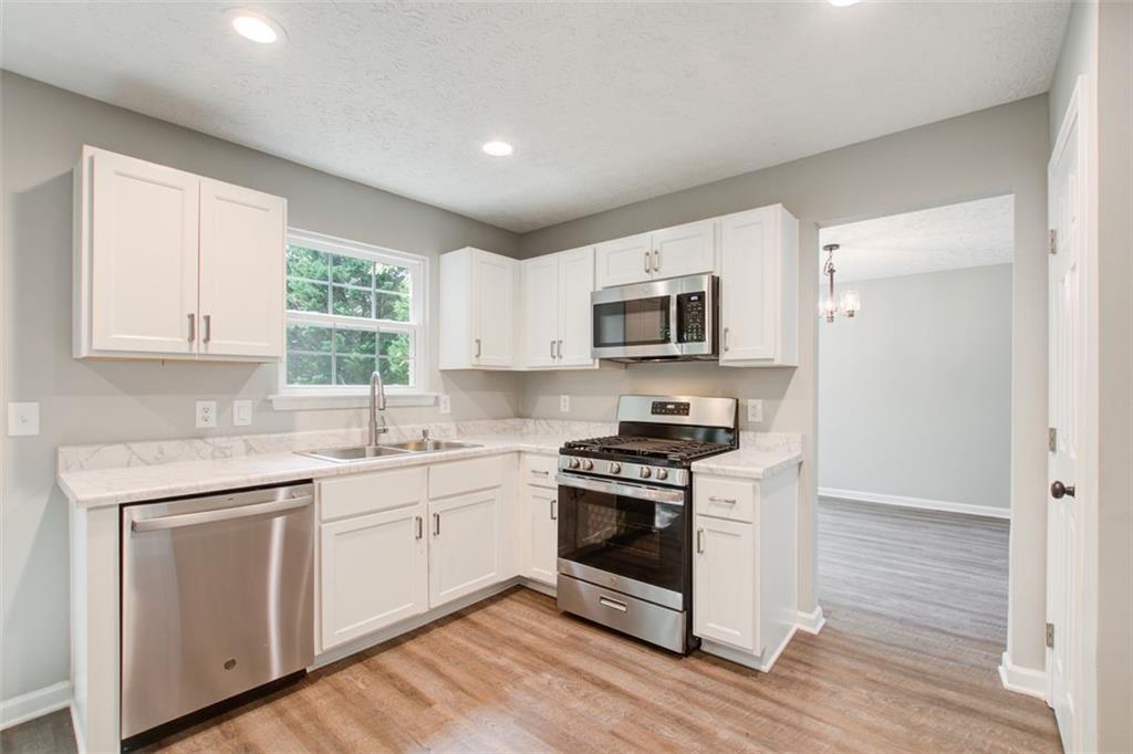 4110 Ridgebrook Bend Cumming, GA 30028 - Photo 13 of 49 a kitchen with white cabinets appliances and wooden floor