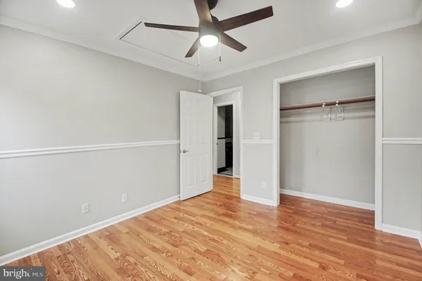 a view of empty room with wooden floor and ceiling fan