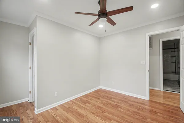 an empty room with wooden floor and ceiling fan