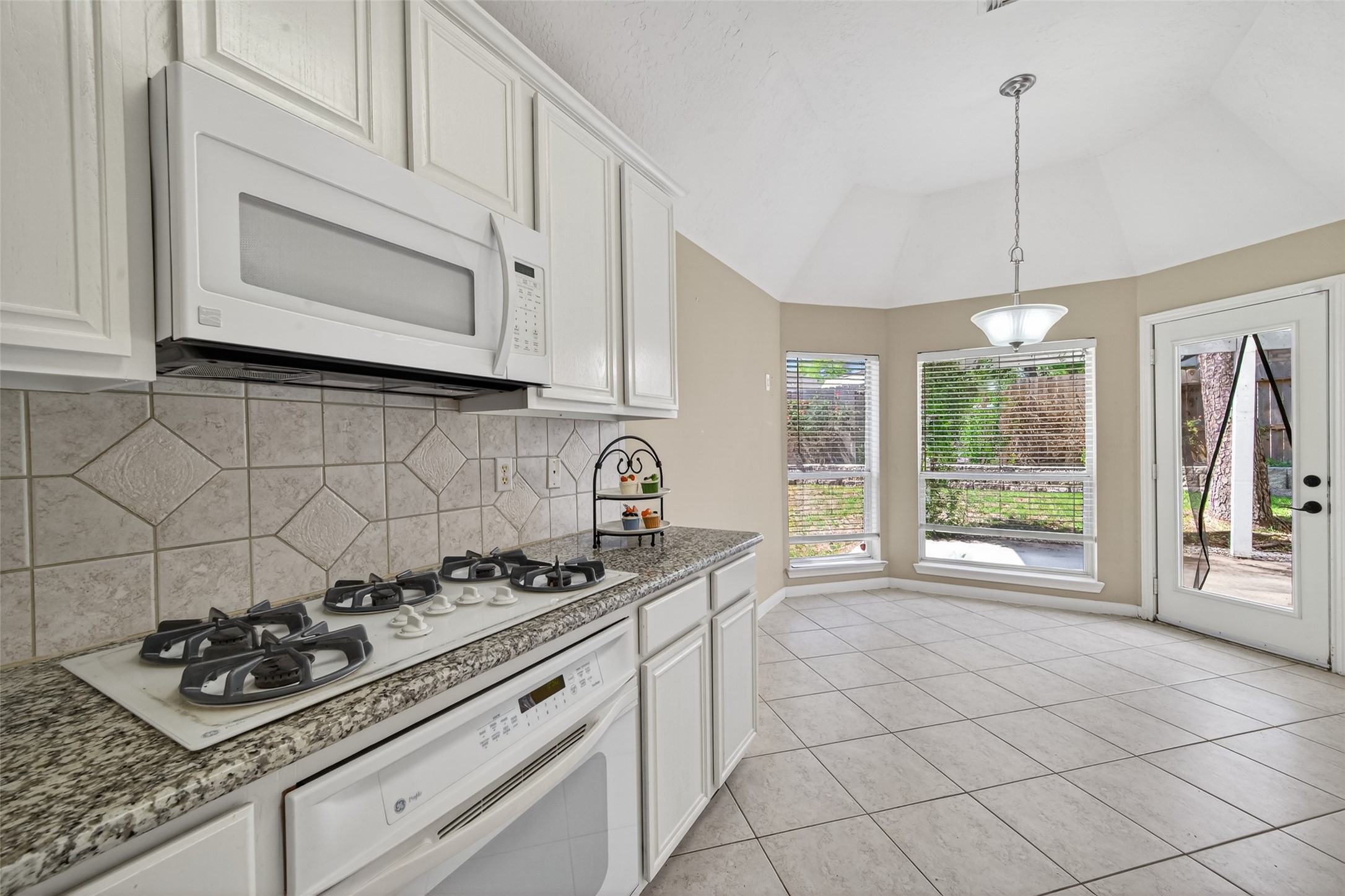 23211 Goldensong Court Spring, TX 77373 - Photo 23 of 46 a kitchen with granite countertop a stove a sink dishwasher and white cabinets with wooden floor