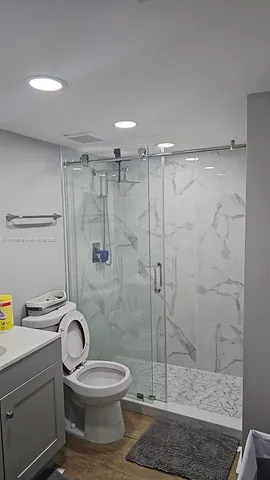 a bathroom with a granite countertop toilet a sink and shower