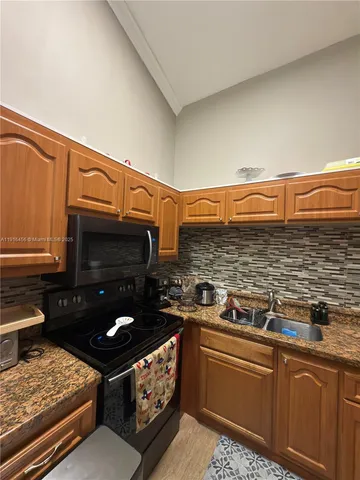 a kitchen with stainless steel appliances granite countertop a stove a sink and a microwave