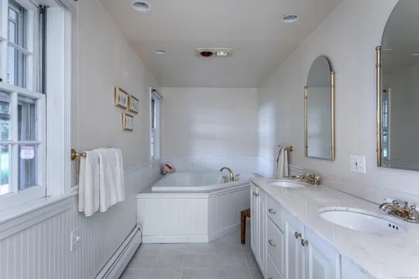 a bathroom with a double vanity sink mirror and bathtub