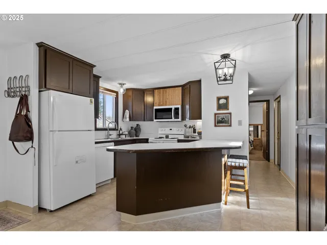 a kitchen with kitchen island a counter top space a sink a refrigerator and cabinets
