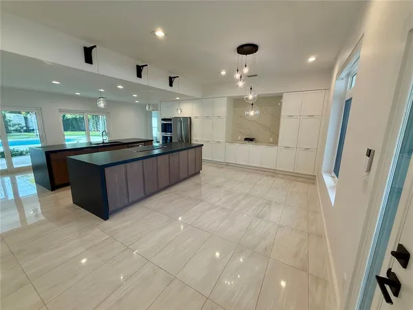 a large living room with stainless steel appliances kitchen island a sink dishwasher a stove and a refrigerator with wooden floor