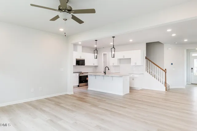 a open kitchen with stainless steel appliances granite countertop a stove a sink dishwasher a refrigerator and a fireplace with wooden floor