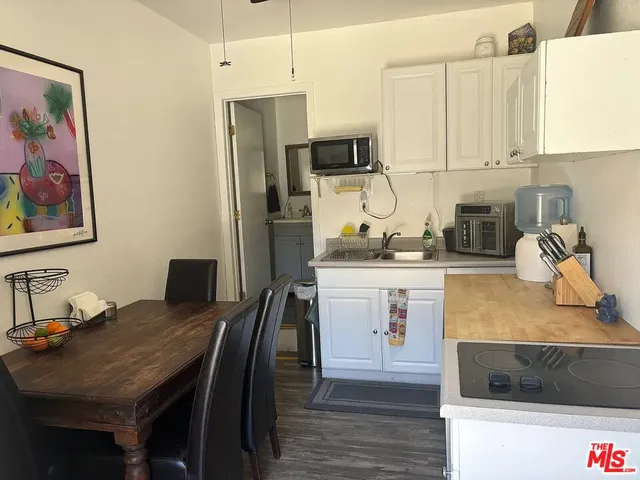 a kitchen with stainless steel appliances granite countertop a stove a refrigerator a sink a dining table and chairs with wooden floor