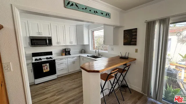 a kitchen with granite countertop a stove top oven a sink dishwasher a dining table and chairs with wooden floor