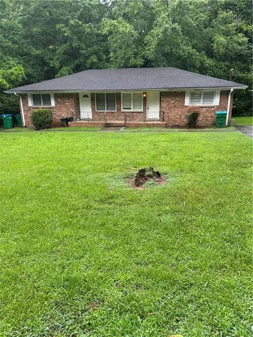 a front view of a house with a garden and trees