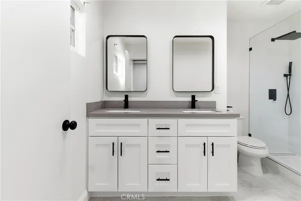 a bathroom with a double vanity sink toilet and mirror