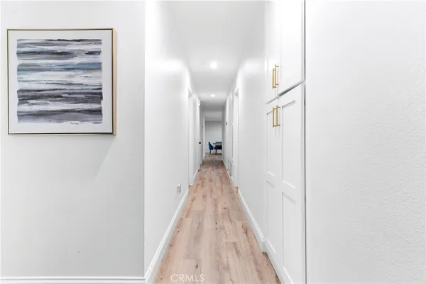 a view of a hallway with wooden floor and a bathroom