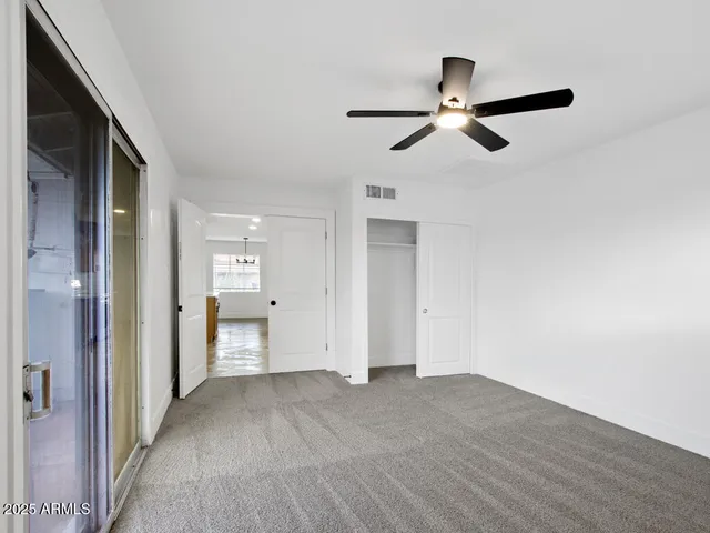 an empty room with a window and a ceiling fan