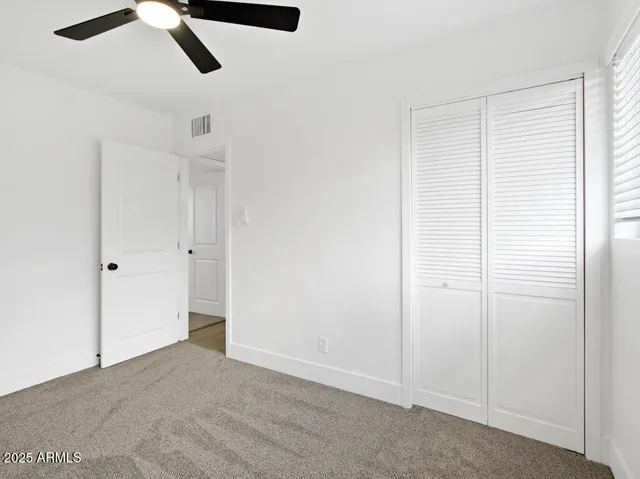 an empty room with windows and fan