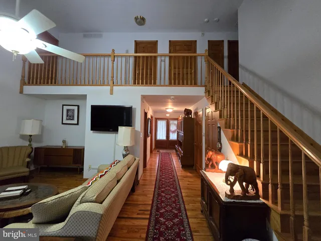 a hallway with a couch and a bookshelf with wooden floor