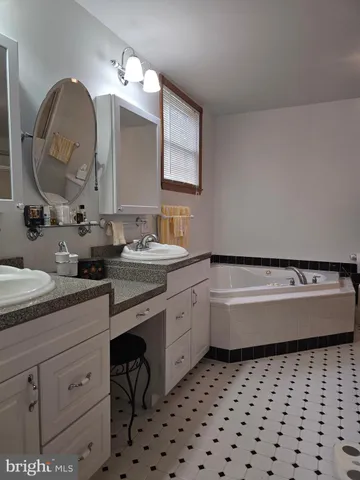 a bathroom with a double vanity sink mirror and bathtub