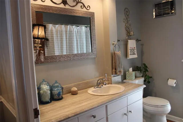 a bathroom with a granite countertop sink a toilet and mirror