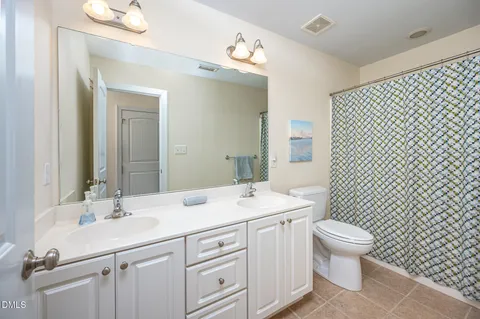 a bathroom with a double vanity sink toilet and a mirror