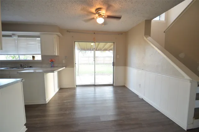 a kitchen with granite countertop a stove a sink and a refrigerator with wooden floors