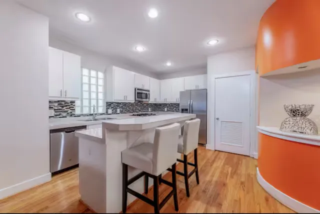 a kitchen with stainless steel appliances granite countertop a white cabinets and wooden floor