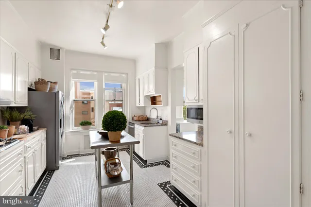 a view of a kitchen with kitchen island granite countertop a refrigerator stove microwave and furniture
