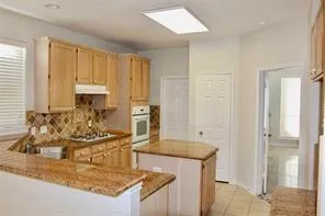 a kitchen with kitchen island granite countertop a sink and a refrigerator