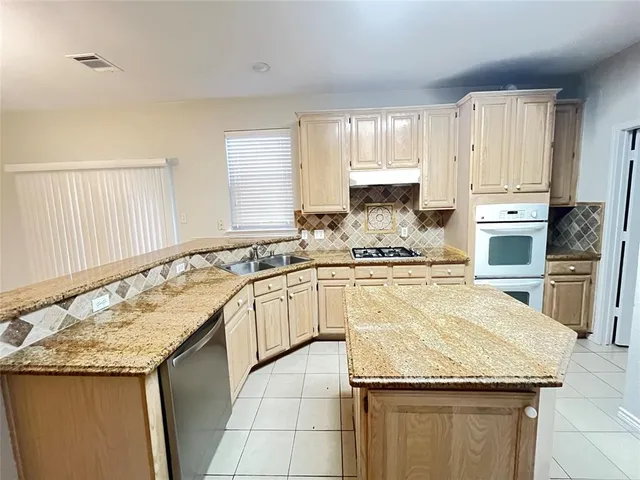 a kitchen with granite countertop a sink a stove and cabinets