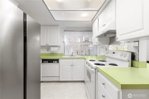 a kitchen with stainless steel appliances a stove a sink and white cabinets