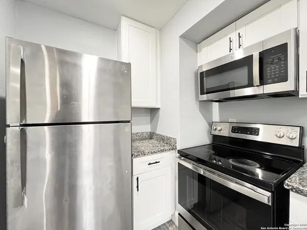 a kitchen with stainless steel appliances white cabinets and a stove top oven