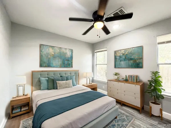 a bedroom with a large bed and a chandelier fan