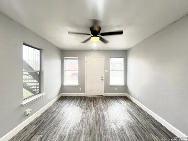 a view of empty room with wooden floor and fan