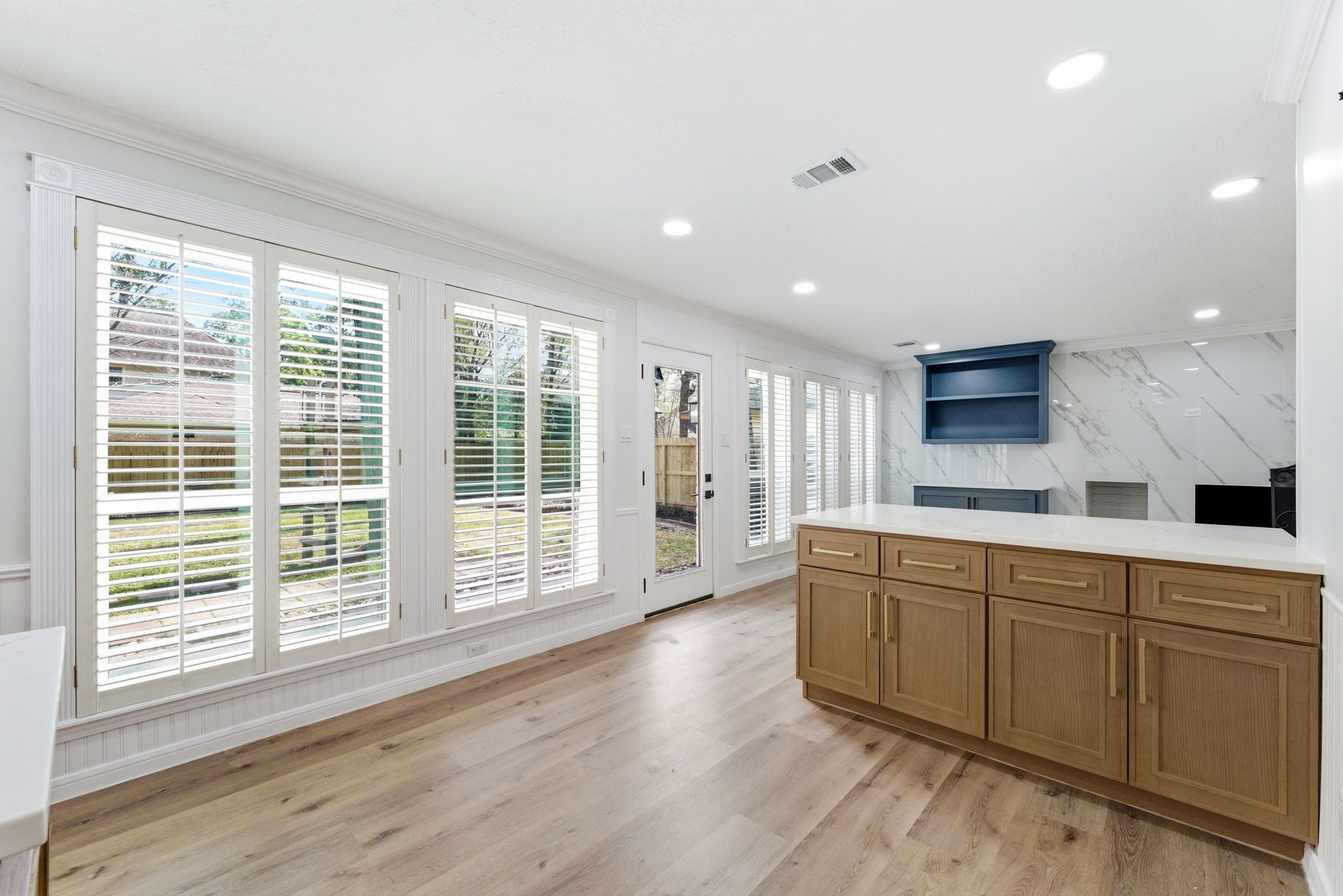 5203 Woodville Lane Spring, TX 77379 - Photo 15 of 50 Sun-drenched and sophisticated. This expansive view captures the seamless transition from morning coffee by the window to evening entertaining around the island. Those plantation shutters aren't just for privacy—they’re for perfect light control.
