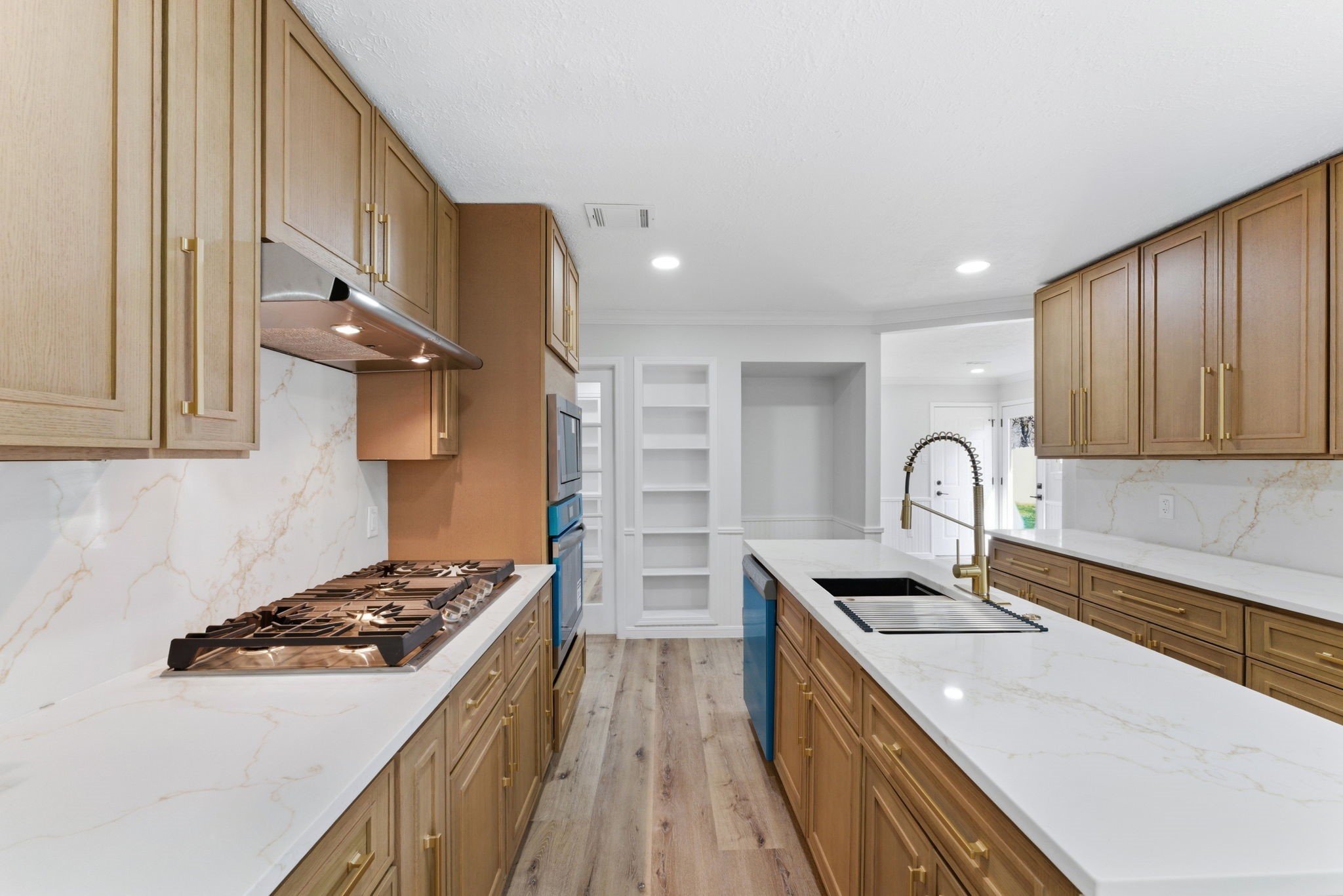 5203 Woodville Lane Spring, TX 77379 - Photo 18 of 50 Between the professional-grade gas range and that stunning gold-toned hardware, this kitchen is a chef’s playground. The marble-veined backsplash adds just the right amount of "wow" without trying too hard.