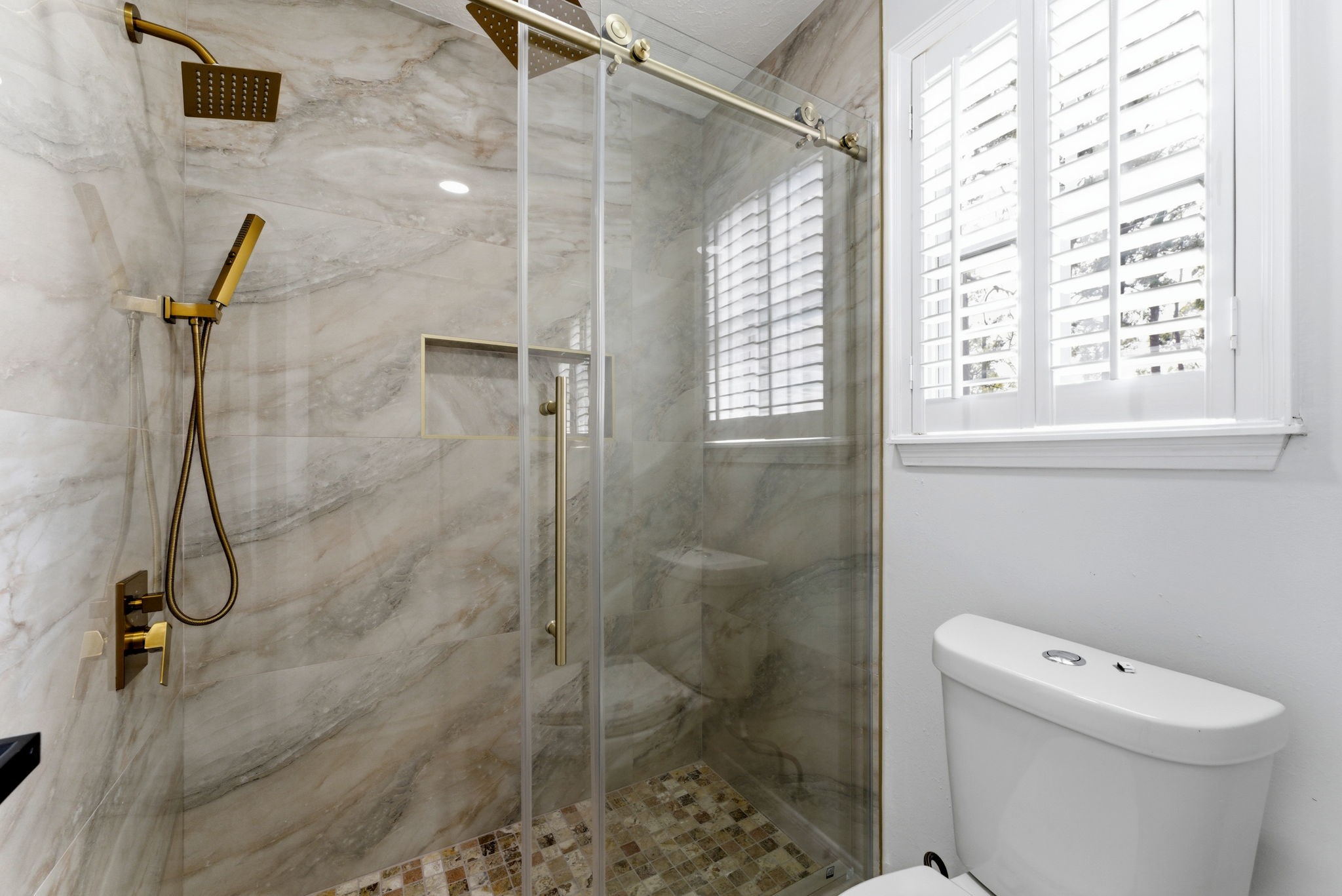 5203 Woodville Lane Spring, TX 77379 - Photo 32 of 50 Step into your daily getaway. This walk-in shower boasts floor-to-ceiling stone-style tile, high-end gold rainfall fixtures, and a sleek glass enclosure for a true five-star experience.