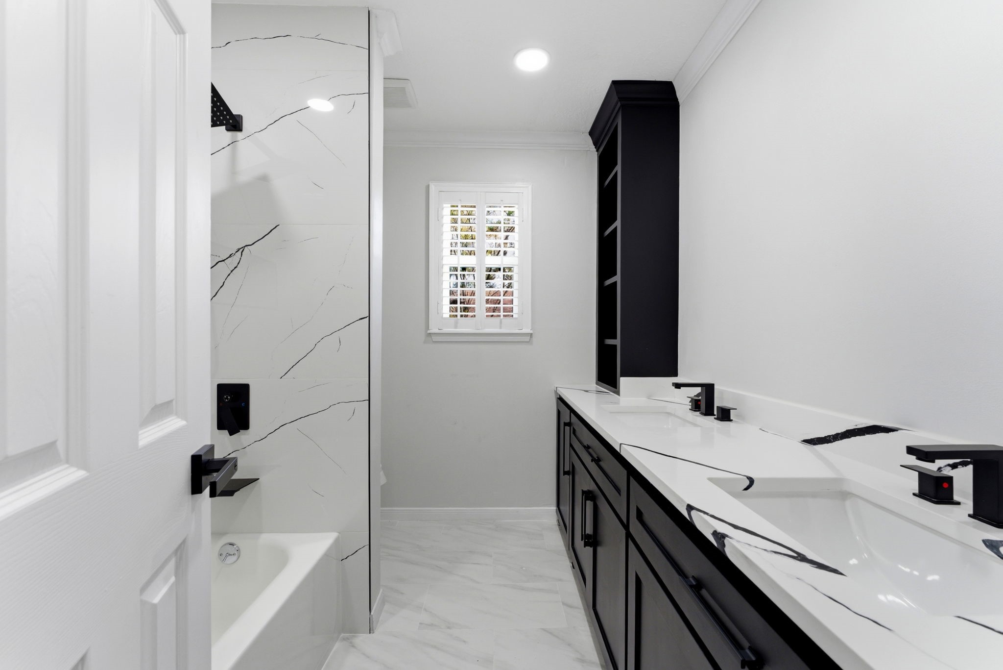 5203 Woodville Lane Spring, TX 77379 - Photo 37 of 50 Indulge in a spa-like experience with this stunning double vanity, featuring bold black cabinetry and dramatic marble-veined countertops.