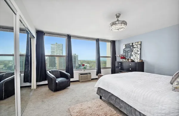 a bedroom with a bed couch and large windows