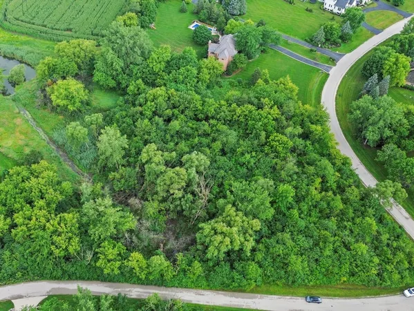 an aerial view of residential house with outdoor space and trees all around