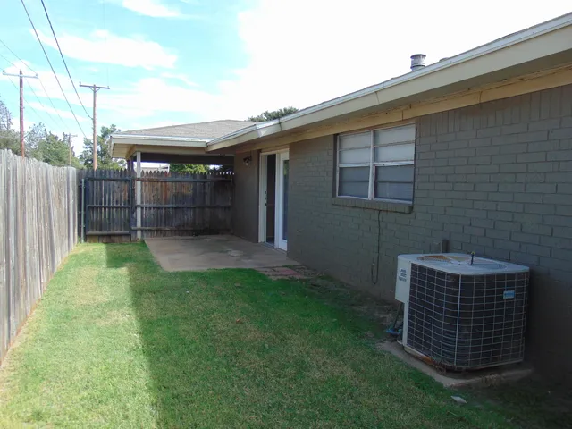 a backyard of a house with plants and wooden fence